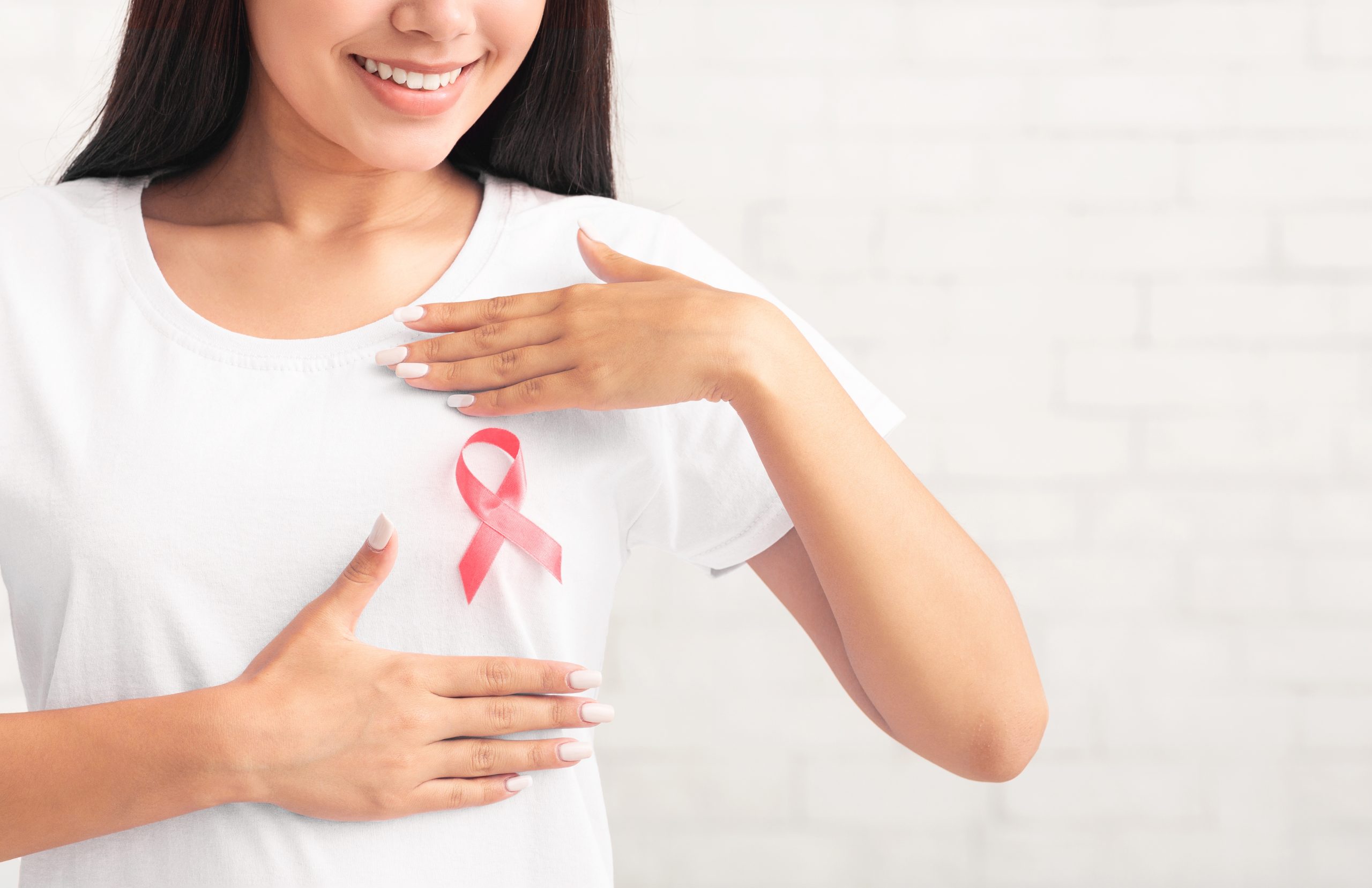 Woman wearing a pink ribbon to promote breast cancer awareness and the importance of breast health screening