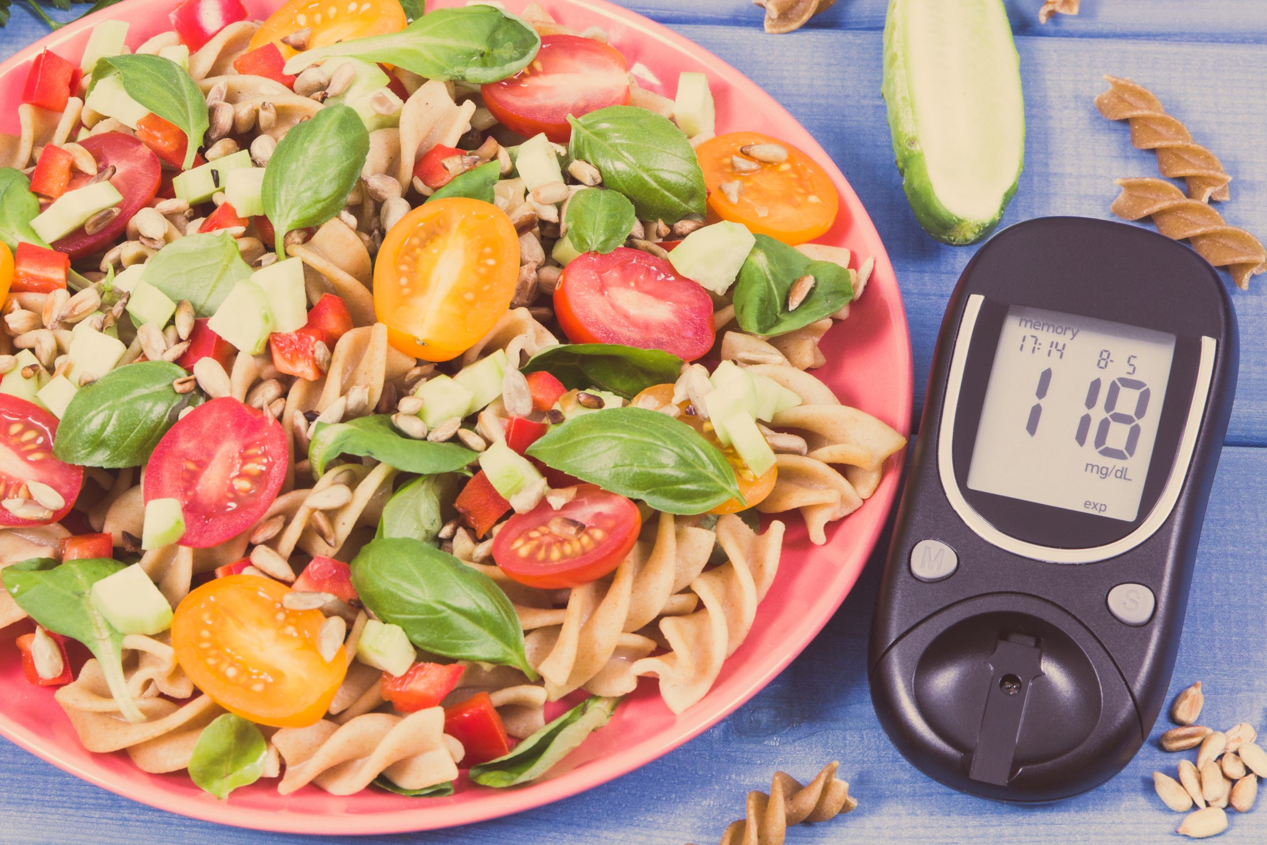 Healthy carbohydrate-rich meal with blood glucose monitor illustrating the relationship between carbohydrates and blood sugar levels
