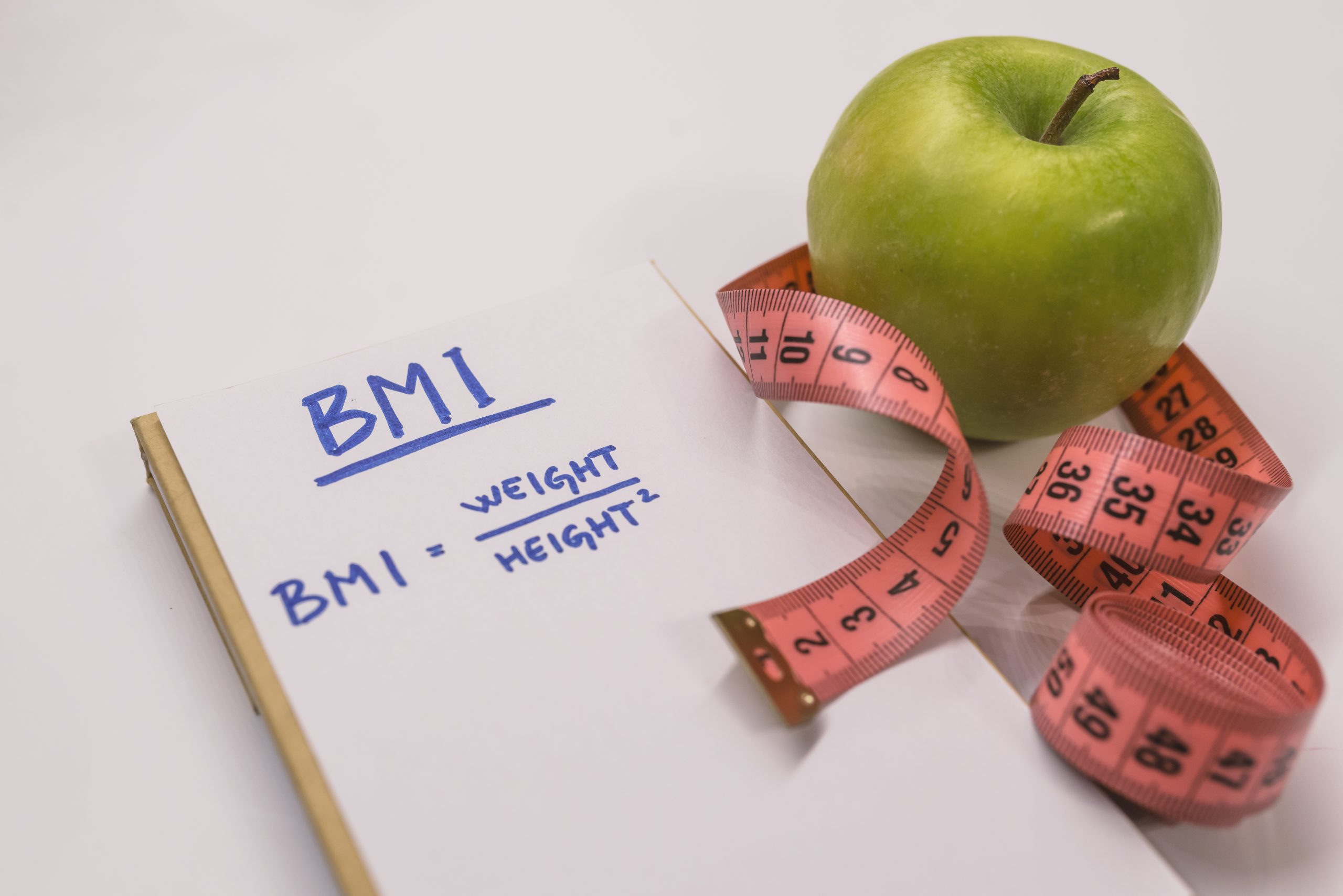 Body Mass Index (BMI) calculation with a healthy green apple and measuring tape, representing weight management and health screening at Evercare Medical Care Centre.