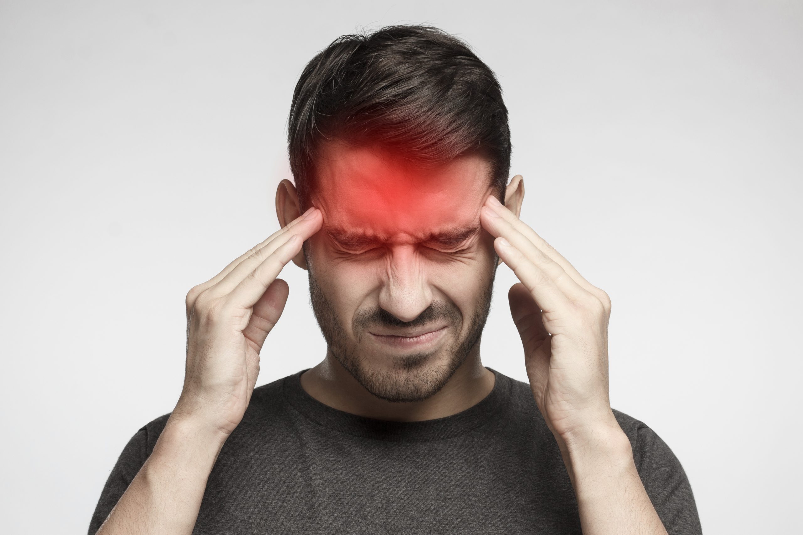 A man experiencing a severe headache by holding both temples, illustrating persistent headache that may require medical assessment and treatment in Penang.