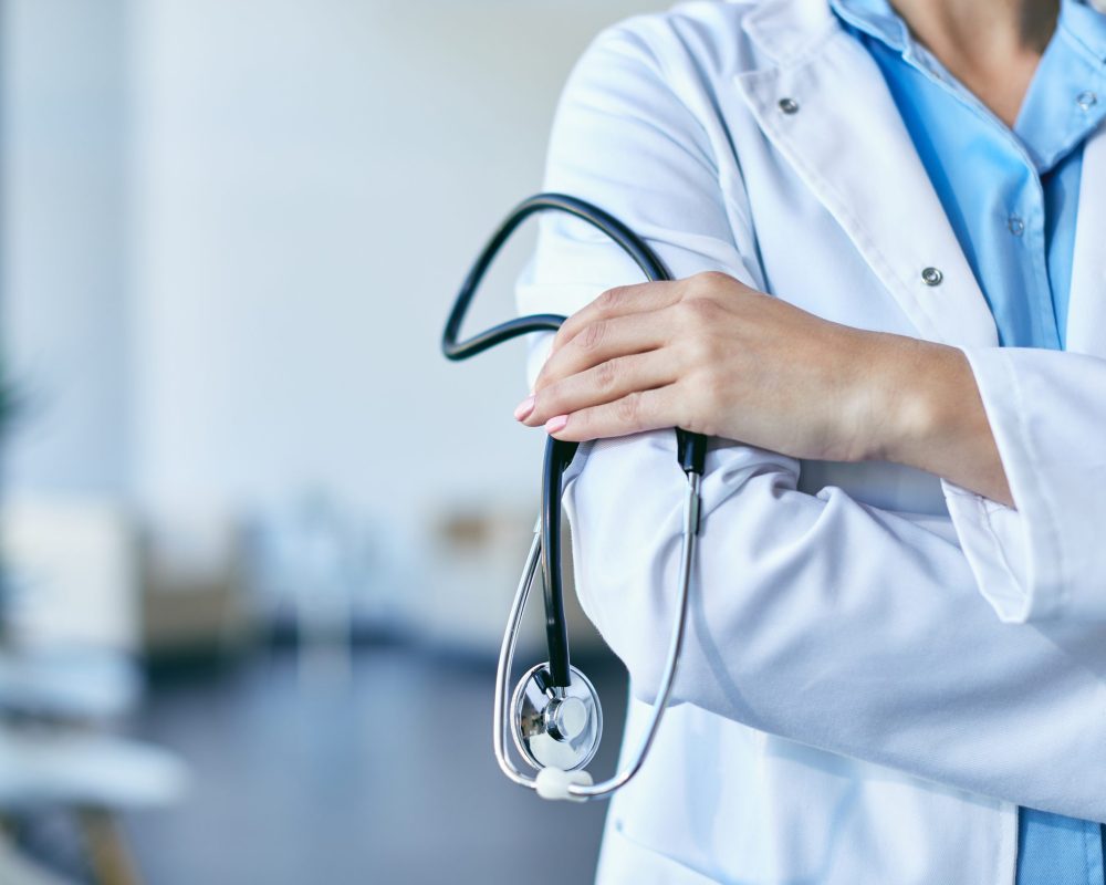 Close-up,Of,Unrecognizable,Doctor,Holding,Stethoscope,While,Standing,With,Arms